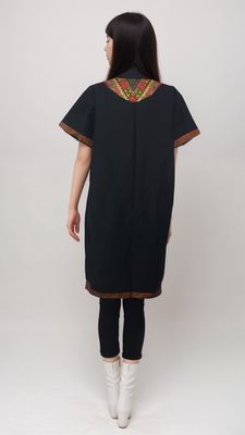 A woman in a black Daishiki shirt dress featuring beautiful embroidery, highlighting her unique fashion sense.