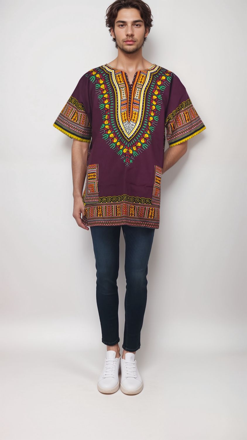 A man models a vibrant reddish and yellow African print shirt, showcasing a stylish burgundy daishiki design.