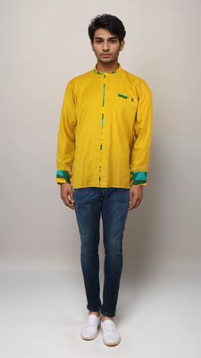 A man dressed in a sunny yellow shirt and denim jeans exudes a relaxed and cheerful vibe in his outfit.