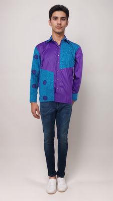A man dressed in a bright purple shirt and denim jeans stands casually, radiating a laid-back yet fashionable vibe.