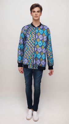 A man confidently sports a vibrant, patterned bomber jacket, showcasing a blend of colors and unique designs.