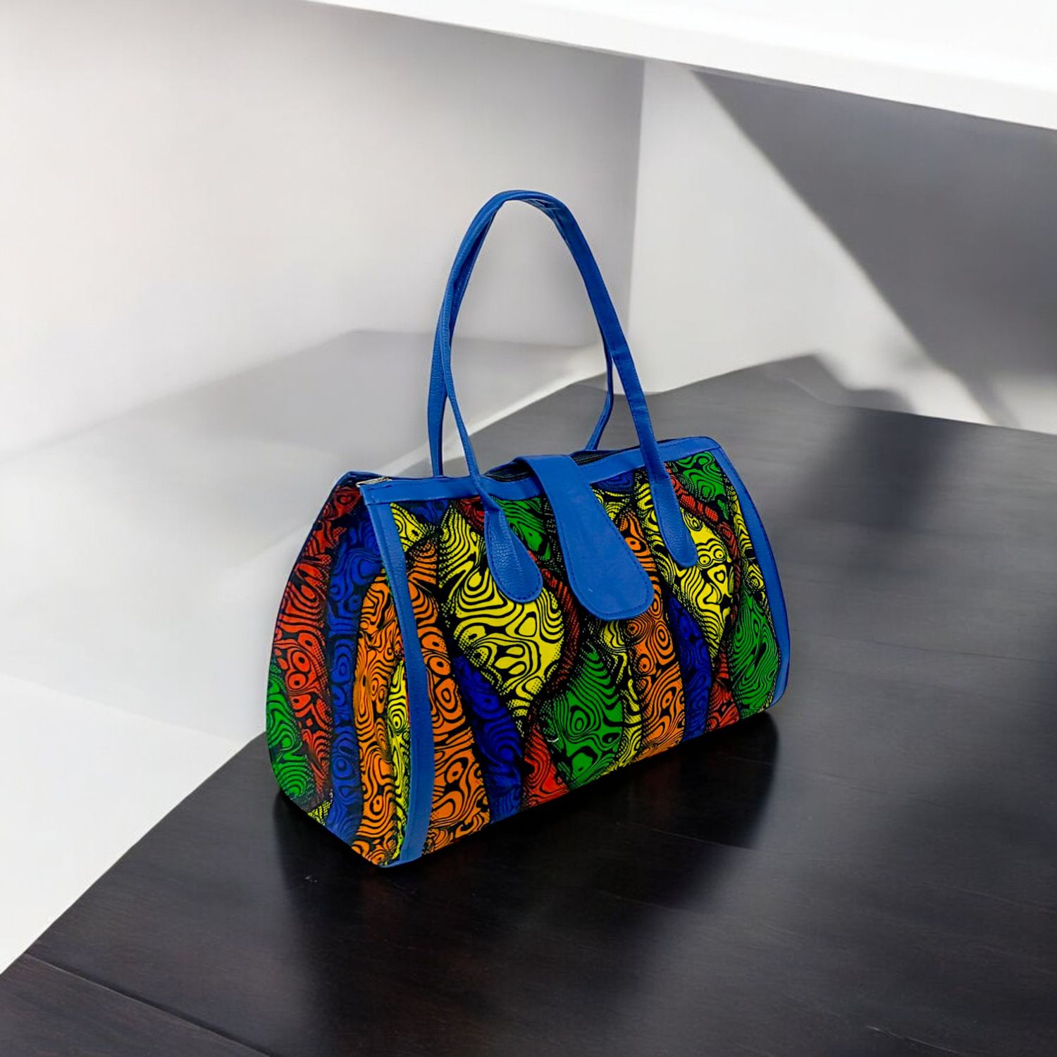 A vibrant handbag featuring a blue handle, showcasing a blend of colors and stylish design