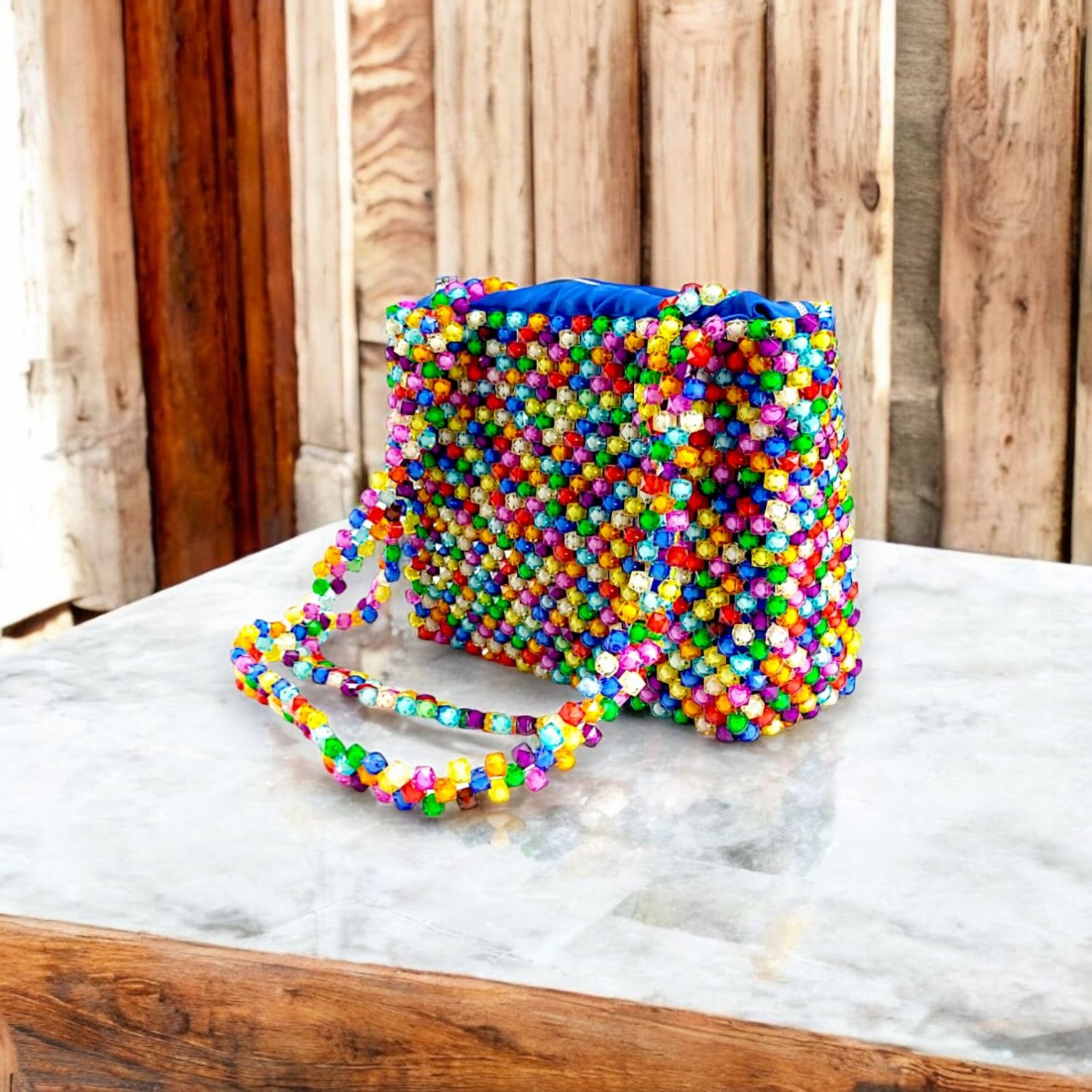 A handbag made of colorful, multicolored beads with a beaded strap and a visible blue interior lining.