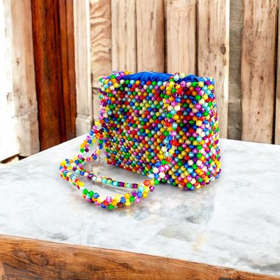A handbag made of colorful, multicolored beads with a beaded strap and a visible blue interior lining.