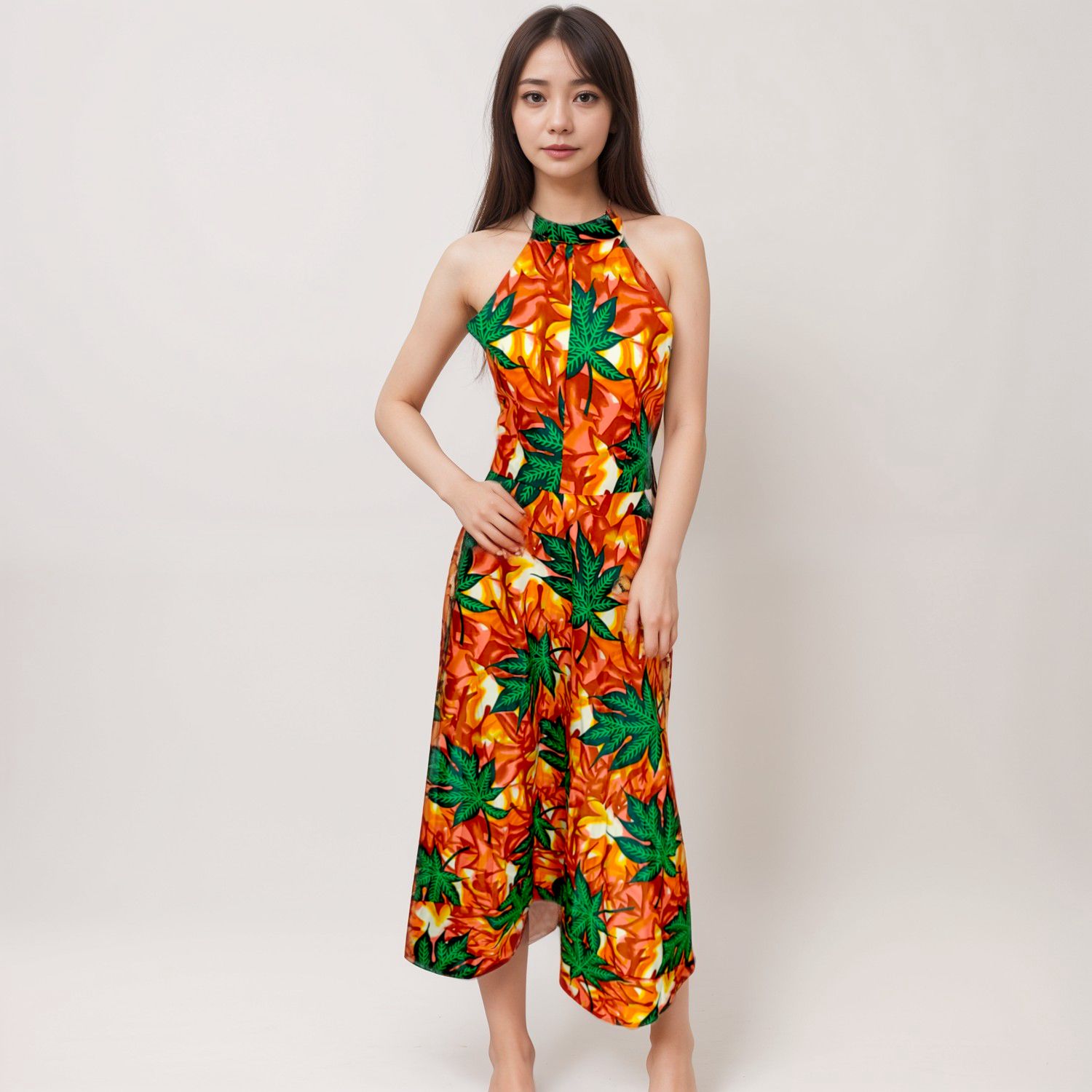 Woman in a colorful halter dress with vibrant green leaves and red-orange patterns stands against a plain backdrop, exuding a lively, bold energy.
