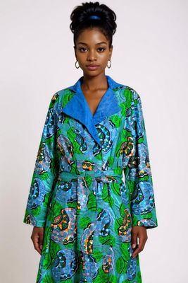 A woman gracefully wears a vibrant green and blue African print robe, showcasing her cultural heritage and style