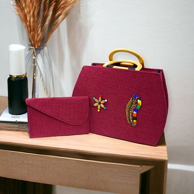 Deep red woven handbag with light wooden handles and colorful beaded designs beside a matching red clutch. Stylish and artistic vibe.