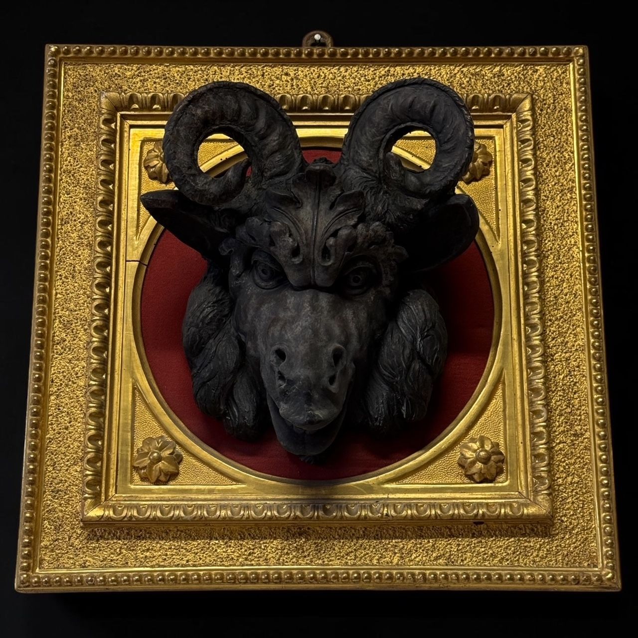 Heraldic trophy with a ram's head in patinated terracotta, gilded frame and red velvet – 19th century Italy