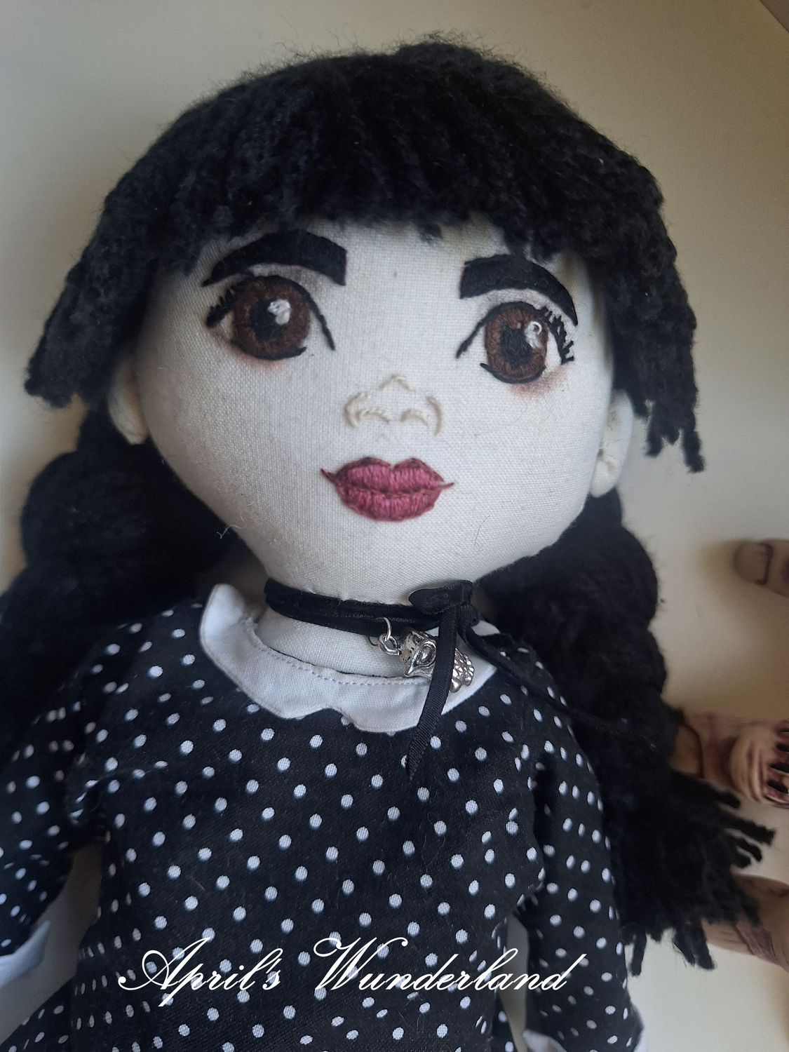 Wednesday Addams - handbesticktes Gesicht mit großen braunen Augen und dem ikonischen gepunktetem Kleid mit weißem Kragen