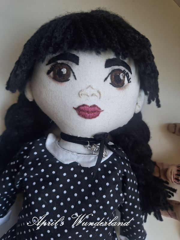 Wednesday Addams - handbesticktes Gesicht mit großen braunen Augen und dem ikonischen gepunktetem Kleid mit weißem Kragen