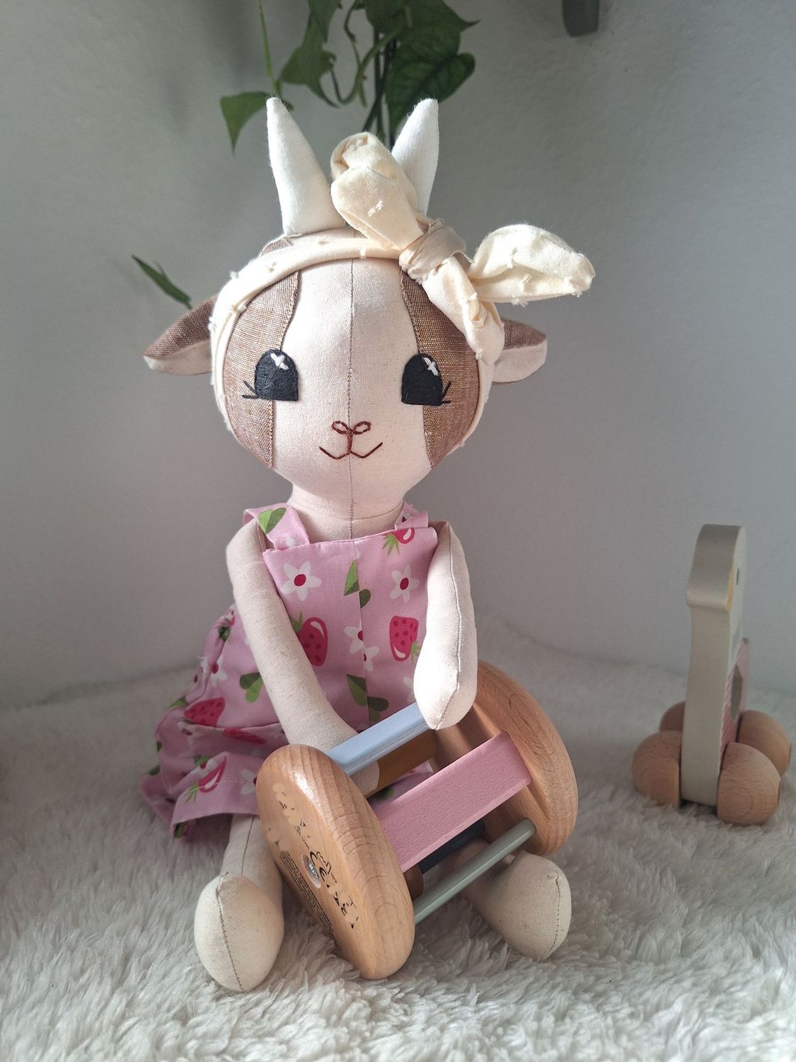 Handgemachtes Kuscheltier 'Lana', Stofftier Ziege, Kuscheltier Ziege „Handgenähte Stoffpuppe mit kleinen Hörnern und beigem Haarband sitzt auf einer weißen, flauschigen Decke.