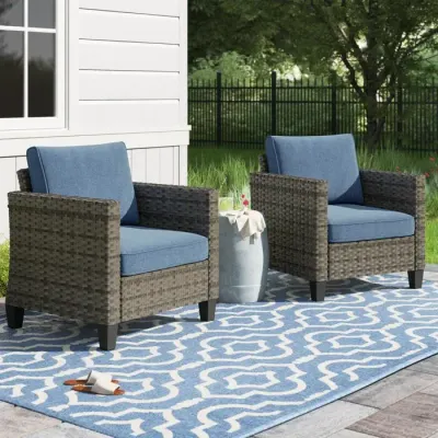 Gray wicker lounge chairs with blue cushions in an outdoor lounge space