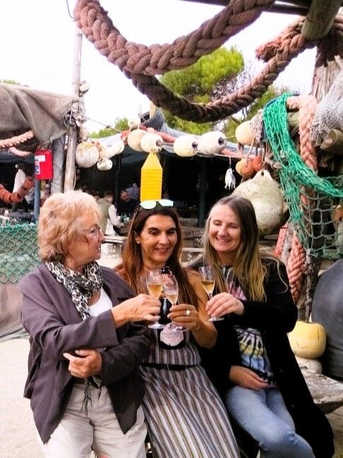 2 Frauen mit denen ich auf den tollen Tag an der Westkueste anstosse. Im Hintergrund ist das OpenAir Restaurant mit alten Fischernetzen und mit alten, schweren Tauen dekoriert. Westkueste, Suedafrika.