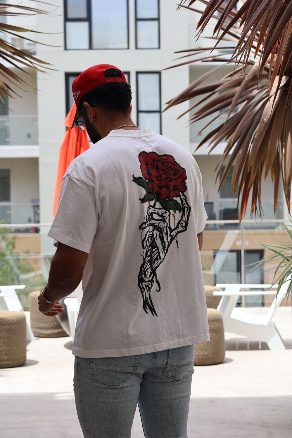 A man wearing  the oversized t-shirt showing the rose graphic on the back
