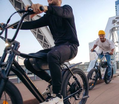 Two riders on a Zooz Ultra Flex electric bike cruising through downtown Los Angeles, CA