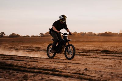 Rider on electric dirt bike tearing through off-road trail