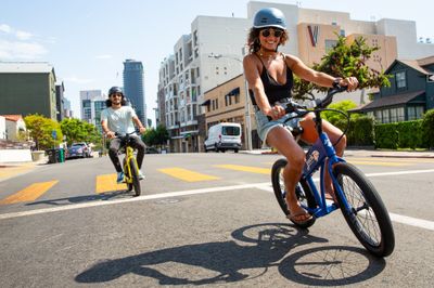 Couple riding JackRabbit electric bikes through downtown Huntington Beach, CA