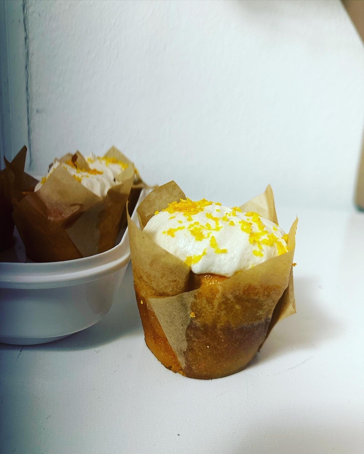 orange cupcake with butter cream cheese icing with lemon zest; red velvet cupcake