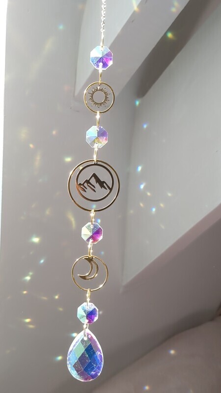 Attrape soleil fait main en pièce unique ou petite série, composé de matériaux durables de qualité. Objet de décoration Feng Shui, l&#39;attrape soleil, invite à l&#39;intérieur de votre maison toutes les belles énergies du soleil en créant un arc-en-ciel lumineux plein de douceur et de magie. Il réharmonise et protège votre intérieur. Montagne, soleil et lune