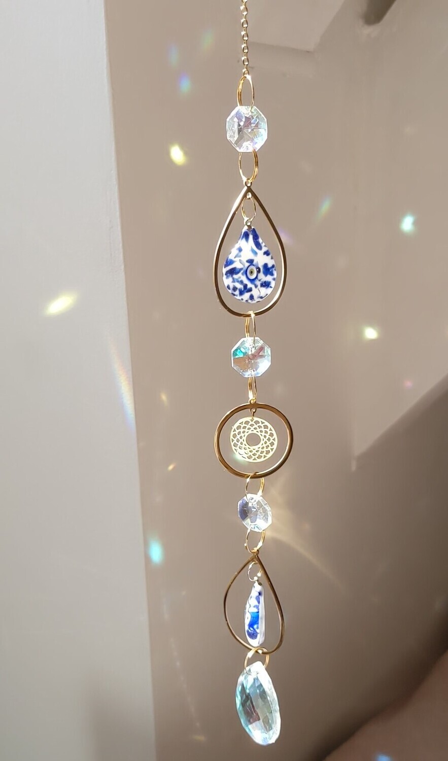 Attrape soleil fait main, composé de matériaux durables de qualité. Nazar en verre tout droit venu d'Istanbul. 
Objet de décoration Feng Shui, l'attrape soleil, invite à l'intérieur de votre maison toutes les belles énergies du soleil en créant un arc-en-ciel lumineux plein de douceur et de magie. Il réharmonise et protège votre intérieur.