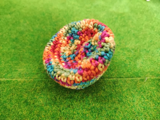 Mini Sitzkissen 5 cm - Haekelkissen Gehäkeltes Miniatur Sitzkissen mit buntem Farbverlauf auf einer grünen Deko Wiese. Farbverlauf in Rot, Orange, Gelb, Grün