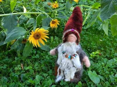 Gefilzte Sammlerfigur Quinn – Höhlenwesen Gefilzter Naturgeist mit weißem Bart und rotbraunem Hut vor Sonnenblumen