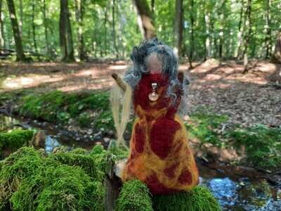 Gefilzte Zauberin Esmeralda Gefilzte Zauberin im Wald mit bemoosten Baumwurzeln