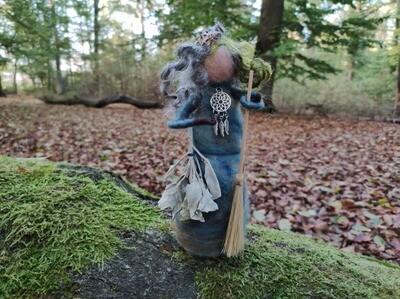 Gefilzte Hexe Circe Gefilzte Hexe Circe mit weißem Salbei, Holzbesen, Metallschmuck in Form einer Traumfänger Kette im Wald mit bemoosten Wurzeln