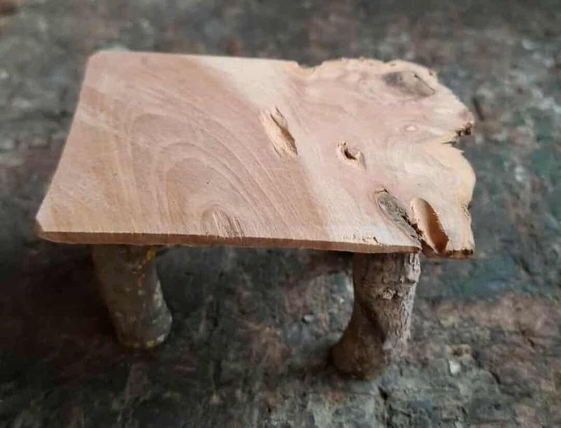 Handgefertigter Holztisch für die Miniatur Wichtelwelt Miniatur Tisch aus Holz auf einer dunklen Holzhobelbank