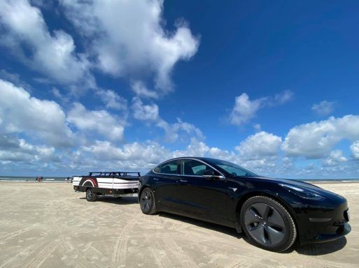 Tesla mit flachem Combi-Camp Country Zeltanhänger am Strand