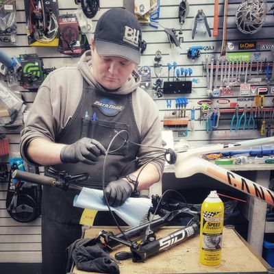 Mécanicien de vélo professionnel effectuant une mise au point sur un vélo de montagne dans l'atelier Bicycles Huard.