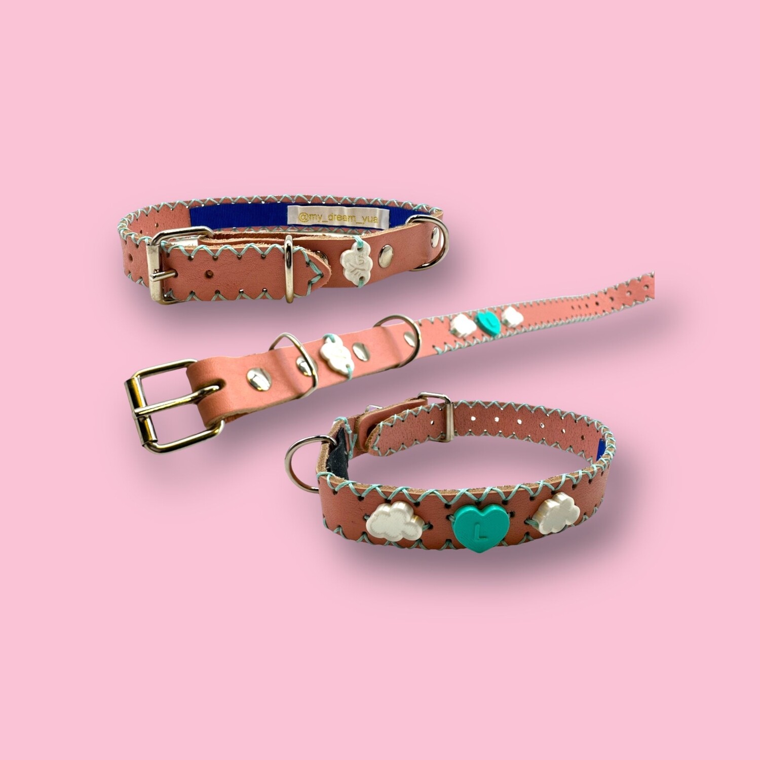 COLLARE in pelle rosa personalizzato con bordatura in contrasto color verde tiffany e charme turchese a cuore con iniziale L e due nuvolette bianche in PLA. La taglia del collare è la S COLLARE in pelle rosa personalizzato con bordatura in contrasto color verde tiffany e charme turchese a cuore con iniziale L e due nuvolette bianche in PLA. La taglia del collare è la S
