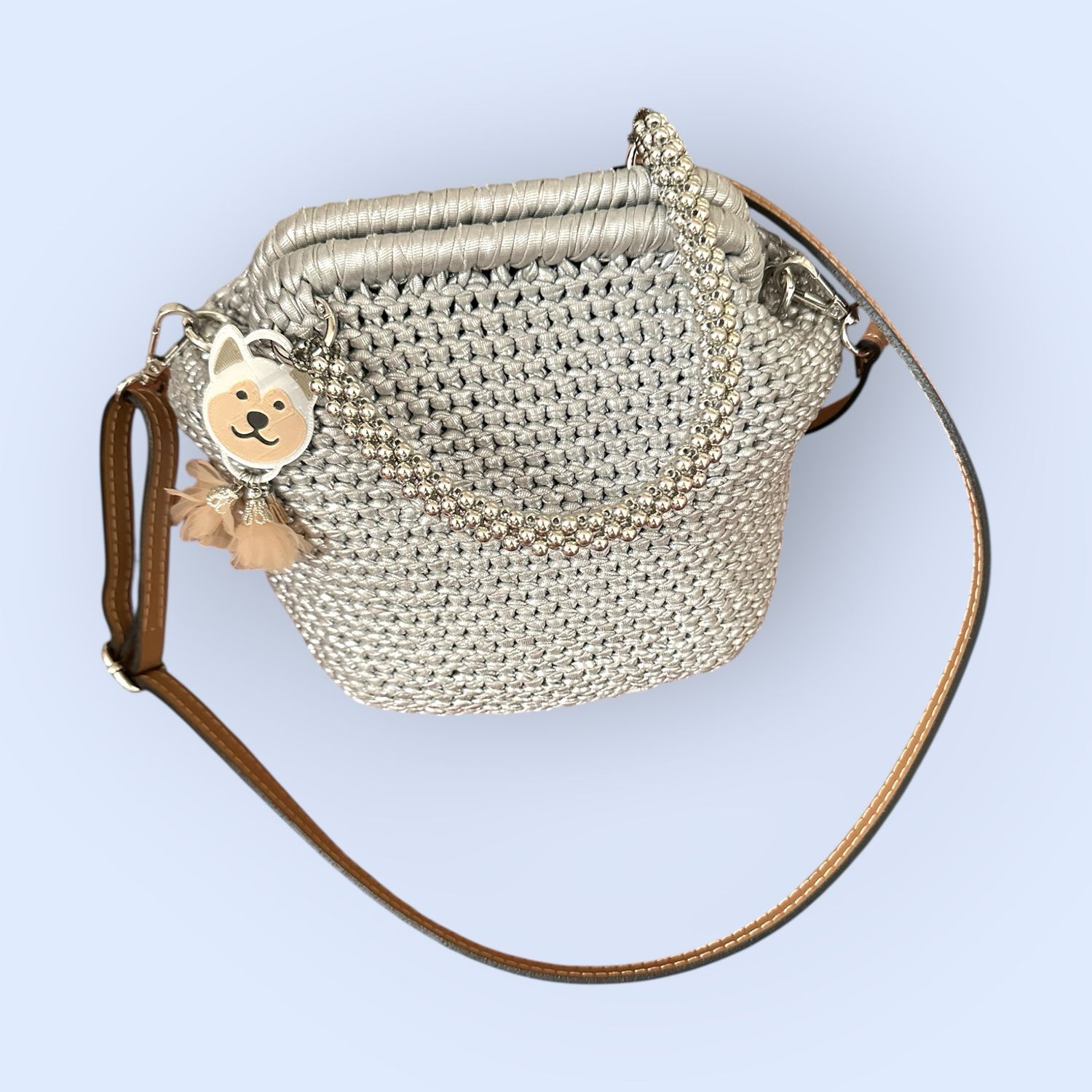Borsa realizzata all’uncinetto con filato similpelle argento rifinita da tracolla in pelle manico con perle argentate e personalizzato con charme in PLA con la faccina dell’Akita Borsa realizzata all’uncinetto con filato similpelle argento rifinita da tracolla in pelle manico con perle argentate e personalizzato con charme in PLA con la faccina dell’Akita