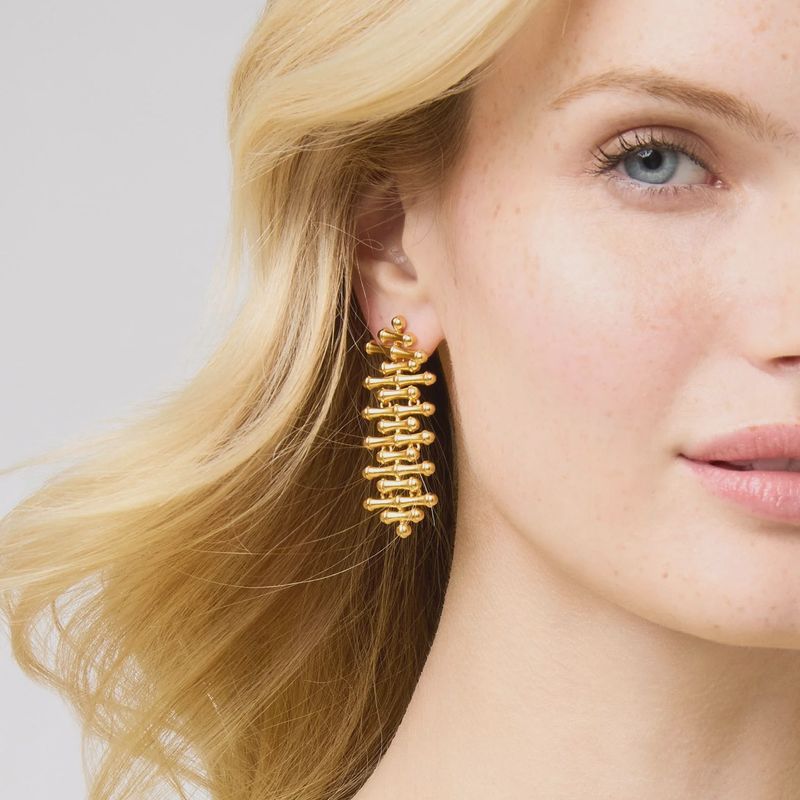 Gold-plated bamboo dangly earrings with 2-inch posts worn in a lifestyle setting, showcasing the 24K gold finish and sculptural design