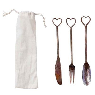 Set of three hand-forged copper appetizer utensils with heart-shaped handles on white background