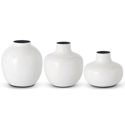 Three white enameled iron vases in graduated sizes arranged together on a plain background