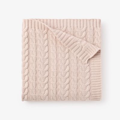 Cream-colored cable knit baby blanket with horseshoe pattern displayed flat on white background