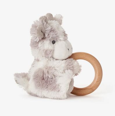 Plush giraffe sensory toy with natural wood ring rattle, displayed in a soft lifestyle setting