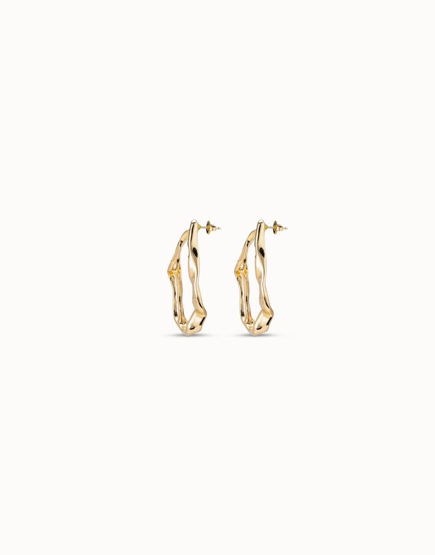 Gold-plated maxi earrings from Uno de 50 with a wave-inspired design, worn in a lifestyle setting