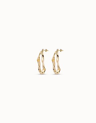 Gold-plated maxi earrings from Uno de 50 with a wave-inspired design, worn in a lifestyle setting