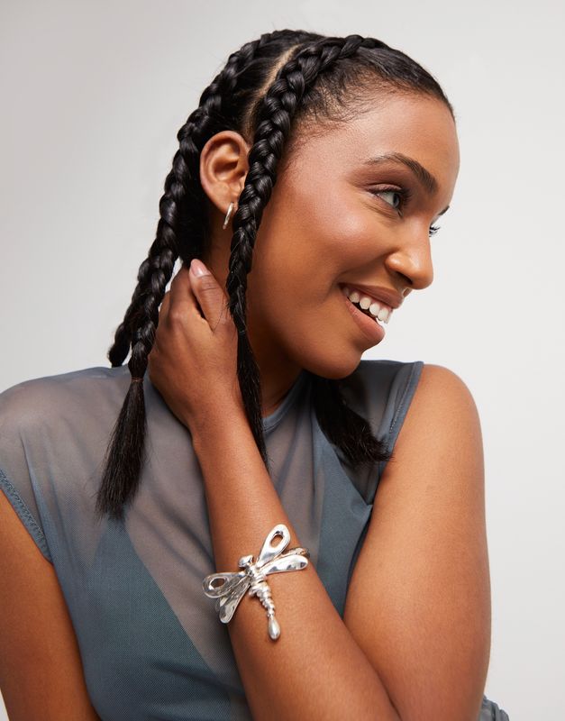 Sterling silver-plated hinged dragonfly bracelet by Uno de 50 worn on a wrist in a lifestyle setting