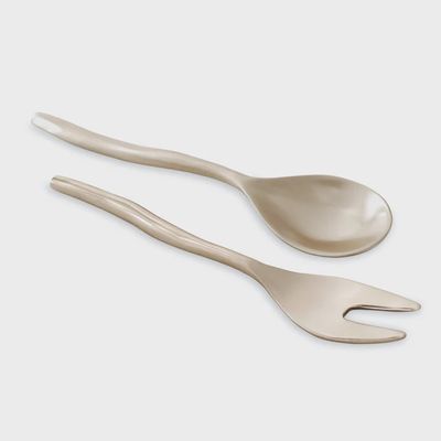Pair of gold-tone salad servers by Beatriz Ball displayed in a table setting with fresh greens and serving dishes