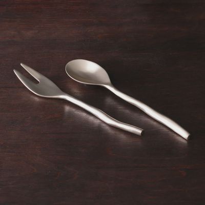 Gold-tone salad servers by Beatriz Ball displayed against a neutral background in studio lighting
