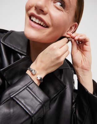 Sterling silver-plated rigid bracelet with white crystal accents, worn on wrist in lifestyle setting