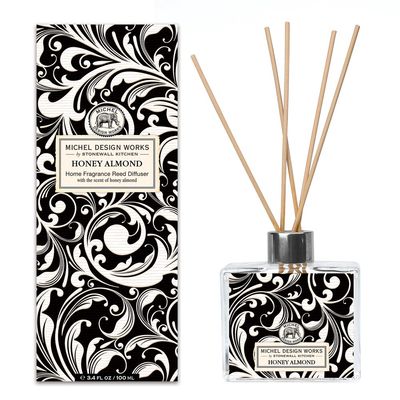 Michel Design Works Honey Almond reed diffuser in a clear glass decanter with wooden reeds on a white background