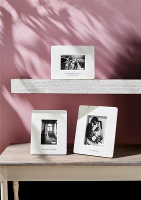 Mr. &amp; Mrs. marble easel photo frame from Mud Pie displayed on a shelf with wedding decor and flowers
