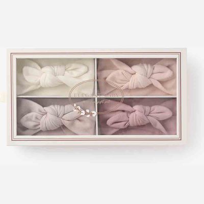 Four soft knot headbands in pastel colors displayed in a studio setting, sized for newborn to 12-month-old babies.