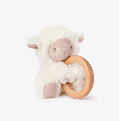 Plush cream lamb toy with wooden ring rattle attached, displayed against a white studio background