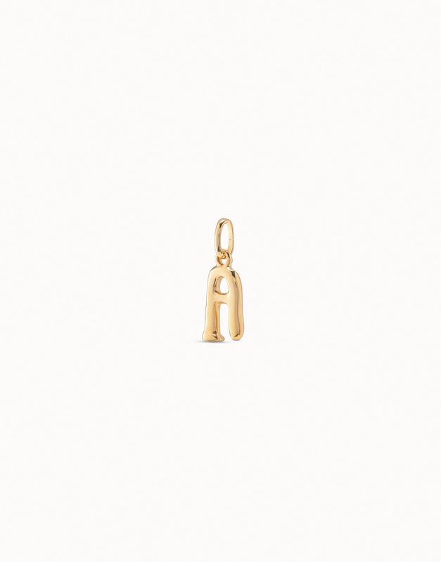 18K gold-plated alphabet initial charm by Uno de 50, handmade, displayed in a lifestyle setting with natural lighting