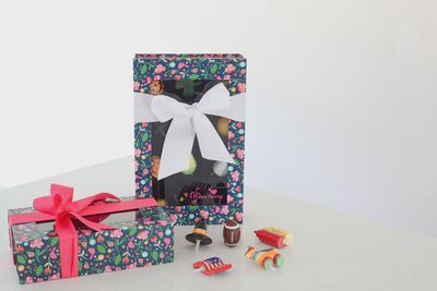 Nora Fleming floral keepsake box with clear lid displaying a collection of decorative minis inside, shown in a home setting